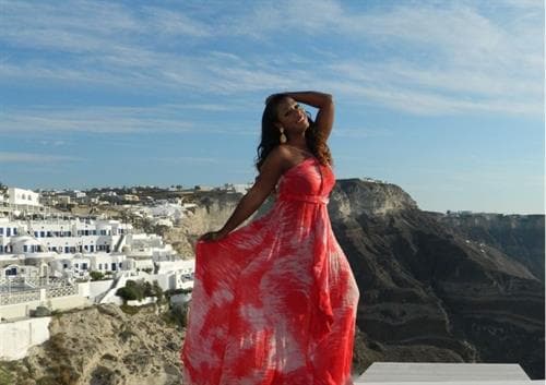 Turks & Caicos photographer and influencer Shenique posing along the hillside in a red floral dress