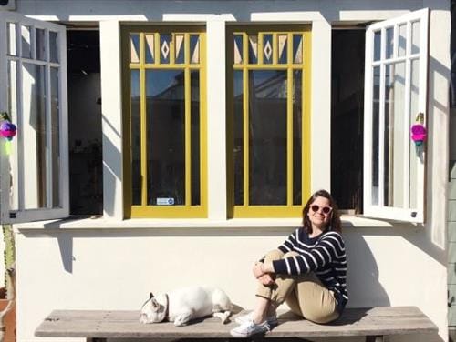 Blogger and travel enthusiast Joana Vaz-Pinto sitting on a bench in the sunshine with her dog