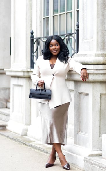 a woman in a professional outfit leaning on a pillar