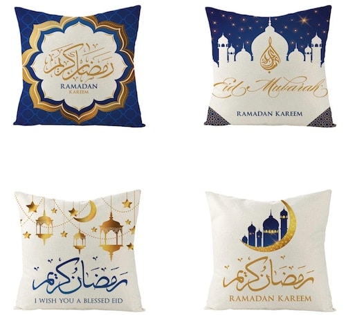 A set of four white honch Ramadan Kareem Pillow Covers with art of lanterns, stars, moons, buildings, and words in blue and gold colors