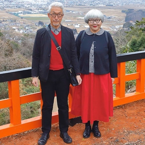 Bon and Pon wearing matching red, blue, and white outfits in front of the pathway that leads to the Kumano Nachi Shrine
