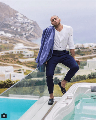 Influencer Dario Fattore standing next to hot tub and pool in business pants and suit jacket on shoulder