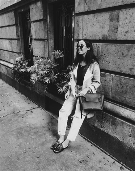 Influencer Sofia Gutierrez leaning against a building in slip on shoes