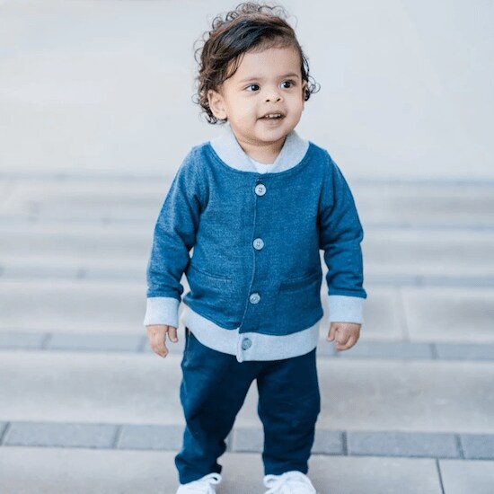 A child wearing a Blue and White Bomber Jacket with blue jeans and white shoes