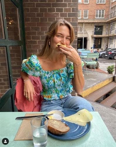 Danish influencer Pernille Wilby enjoying cheese at an outdoor cafe