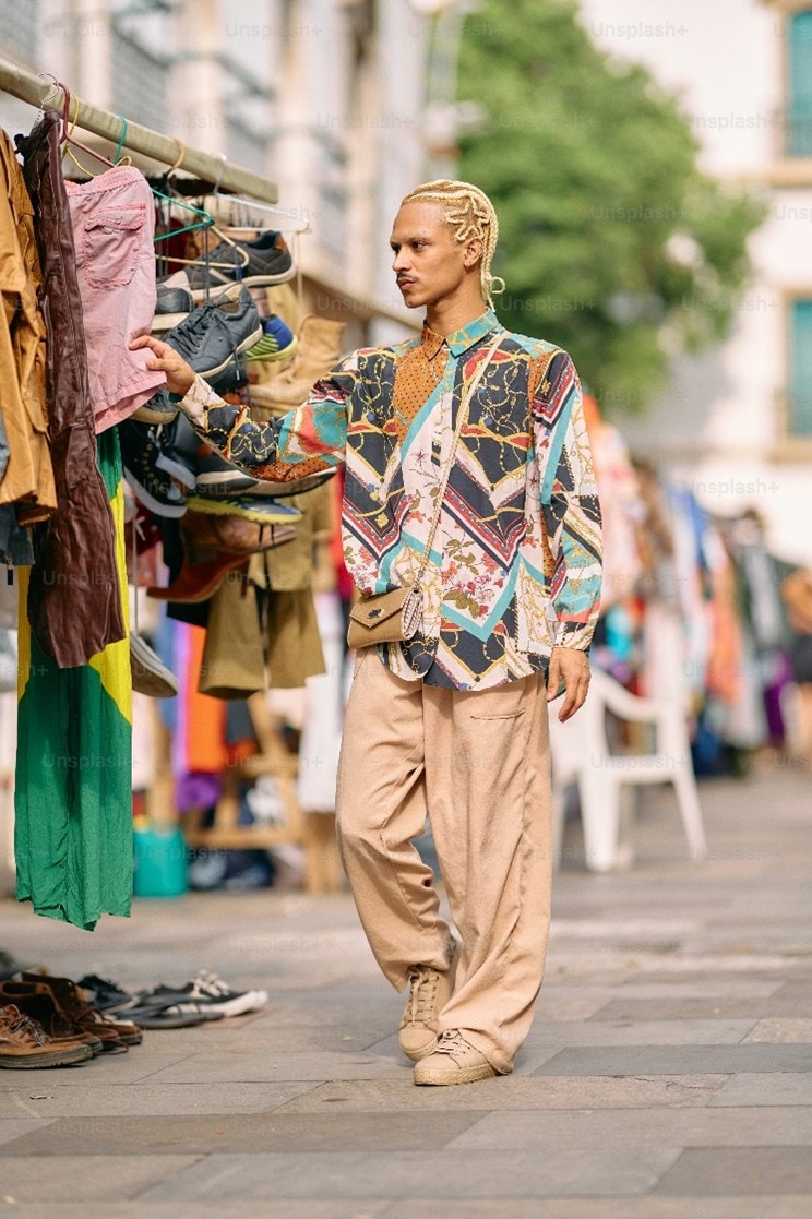 man walking alongside a rack of clothes