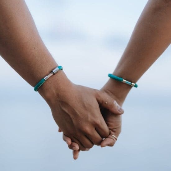 Two people wearing sea turtle legend bracelet holding hands
