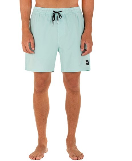 Barefoot male model dressed in Hurley’s valley board shorts for men in the color called Light Dew which is a bright, sky-blue shade.