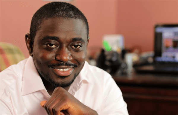 Ademola Ogundele, Nigerian influencer and founder and CEO of popular music website, NotJustOk smiling in front of desk