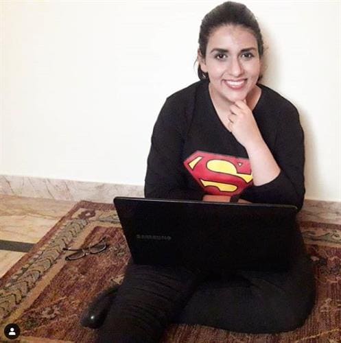 Pakistai influencer, bogger & mobile journalist Sarah Peracha smiling and sitting on the floor with her laptop