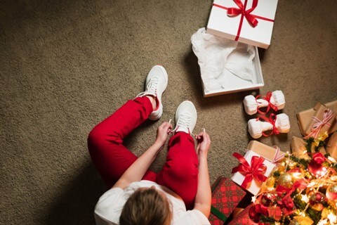 Overhead view of a person who has opened a present with two dumbbells and white sneakers.