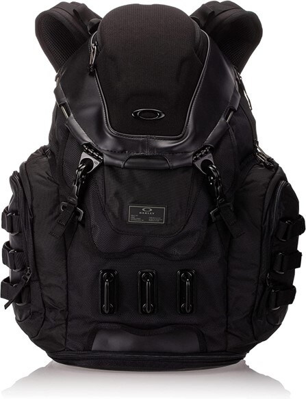 A black Oakley men’s Kitchen Sink versatile backpack featuring padded side-access sleeve for 17" laptop and brushed media pocket at the top for protective storage. The Oakley rubber logo and three hooks are featured on the front. 
