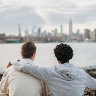 two friends embracing while viewing a city skyline