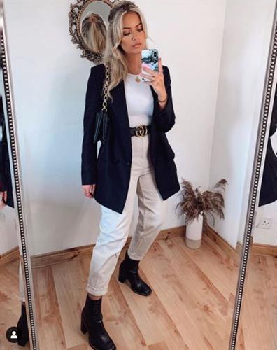 Irish influencer Melissa Riddell taking a selfie in a black blazer, khaki pants, and black boots