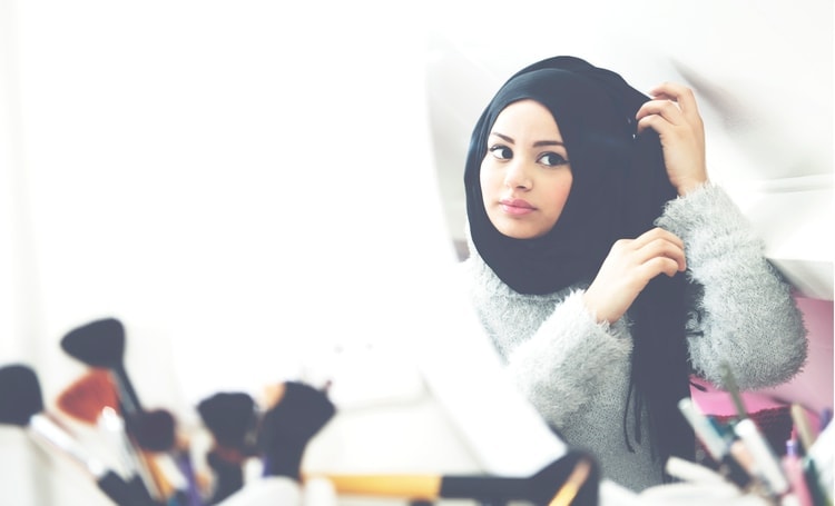 Ruba Zai looking at herself in hijab