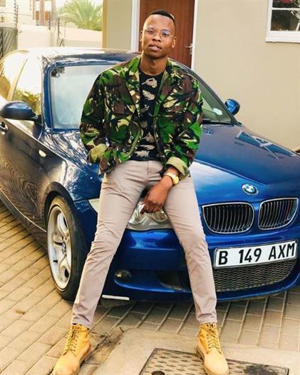 Actor, comedian, and influencer Mjamaica sitting on a blue BMW