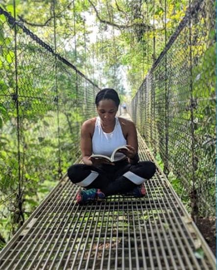 Caribbean influencer and book lover Cindy Allman reading on a bridge