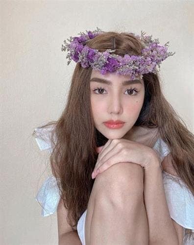 Thai influencer Archita Siri posing in a white dress and floral crown