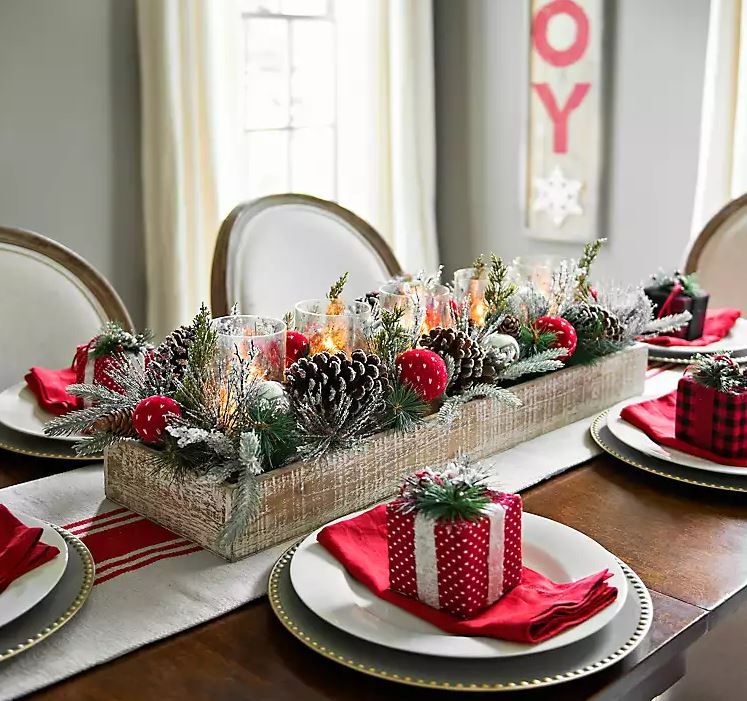 holiday table centerpiece with pinecones, candles, and assorted plants on dining table
