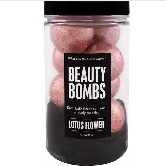 A black container full of eight pink Da Bomb Beauty Bath Bombs with a black label full of white letters and words