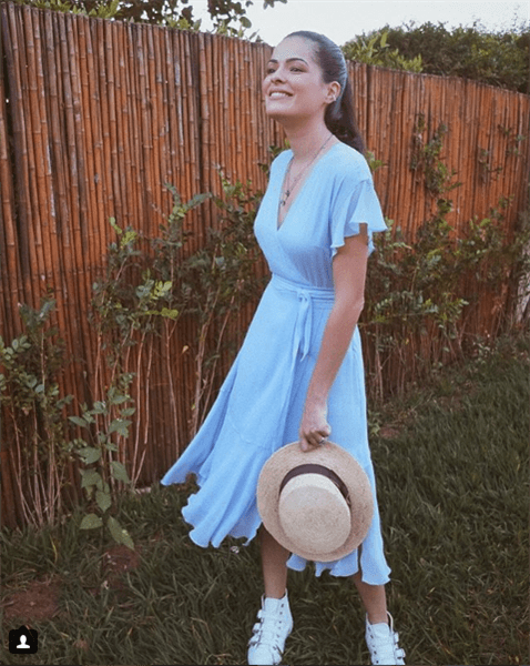 Influencer Mariah Bernardes Maia wearing baby blue dress and white sneakers in the grass