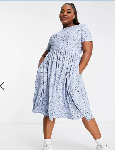 Model posing in the floral light blue plus-size dress by Simply Be, paired with white socks and white sneakers