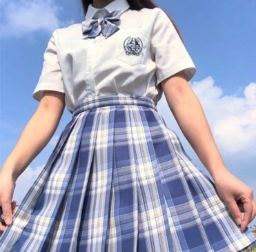 Model in nature, wearing the Harajuku pleated skirt with a white shirt and a matching ribbon