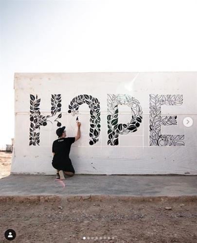 Illustrator and influencer Stefan Kunz painting the word hope on an exterior wall