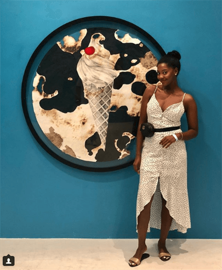 Influencer Afua Rida wearing polka dot dress posed in front of ice cream painting and blue wall