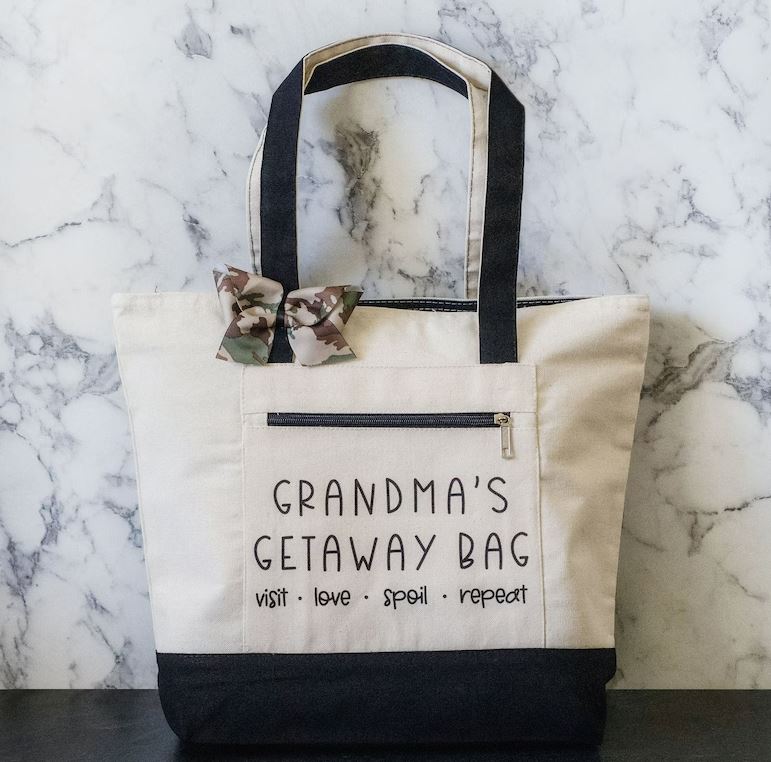 image of a canvas that that reads grandma's getaway bag, visit, love, spoil, and repeat with a brown and gray bowtie on strap