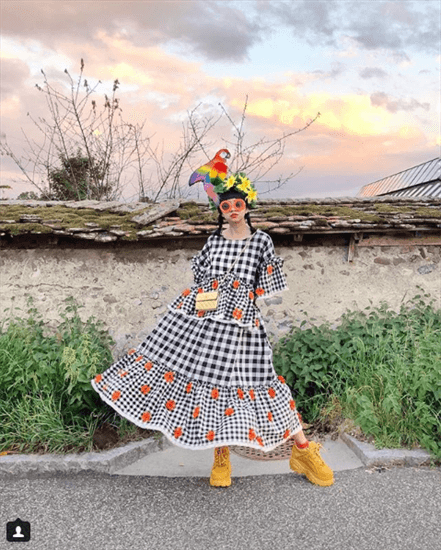 Influencer Diana Rikasari wearing plaid and floral dress with chunky yellow shoes and parrot headress