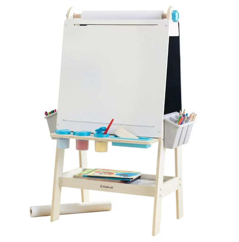 kid sized art easel with blank white canvas, pencils, paintbrushes, crayons, and books on the bottom shelf