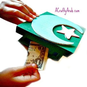 a blue wooden box with a moon and star and hands putting money into it