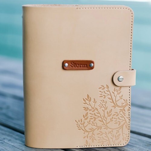 A pearl-colored leather Personalized A5 Organizer Agenda with an embossed tree on the bottom right and snap closure