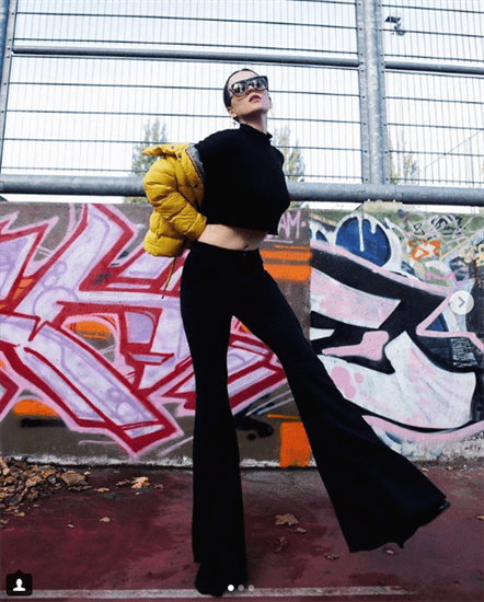 Influencer Andy Torres wearing black cropped top and flare pants with yellow puffy coat