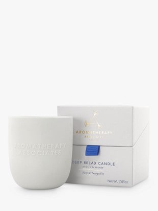 Light gray Aromatherapy Associates candle in front of its luxurious box with gold letters and dark blue ribbon