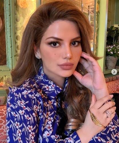 Portrait of makeup artist and Qatari influencer Anam Falak in a blue print blouse 