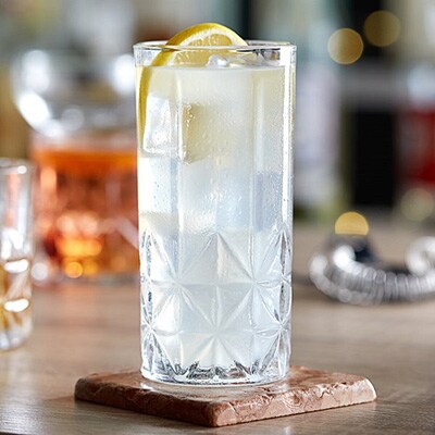 Acopa Gardenia 13 oz. Highball glass with a vintage design shown served with a drink and lemon slice