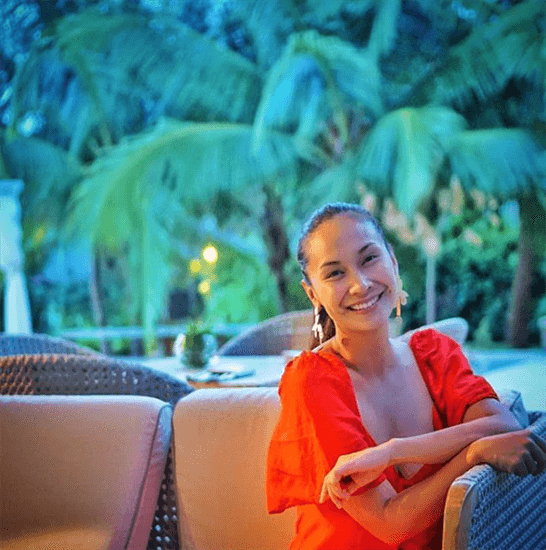 Influencer Patty Laurel Filart sitting on outdoor couch in red dress