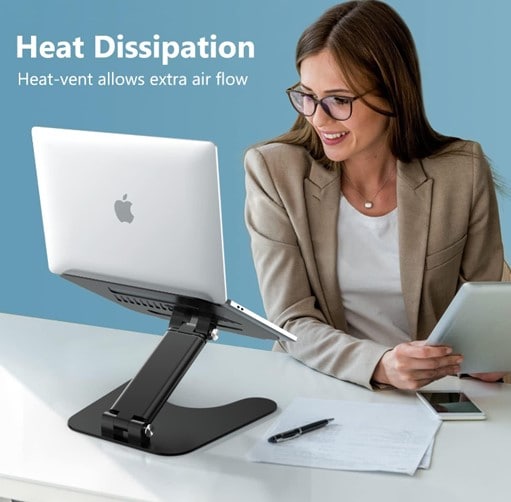 Woman sitting at a desk with papers and a laptop on a black collapsible stand before her