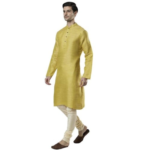 A man wearing a gold Ethnix Men’s Indian Classic Collar Fine Textured Cotton Kurta Tunic Pajama Set with white pants and brown slippers