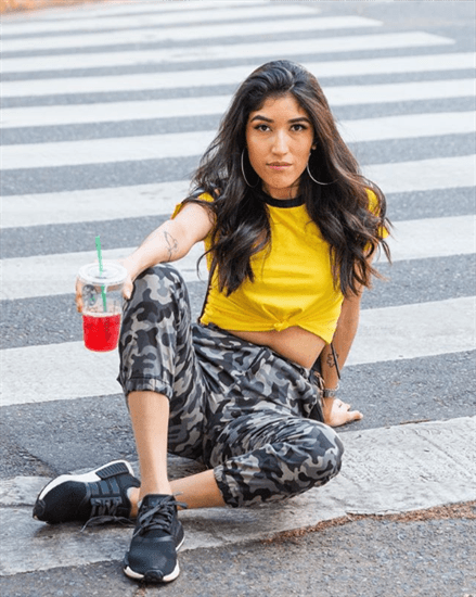 Blogger Yoana Marlen sitting in crosswalk wearing camo pants holding red starbucks drink