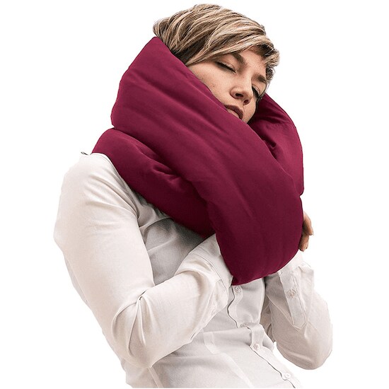 A woman holding Burgundy Huzi Infinity Pillow around her arms and head