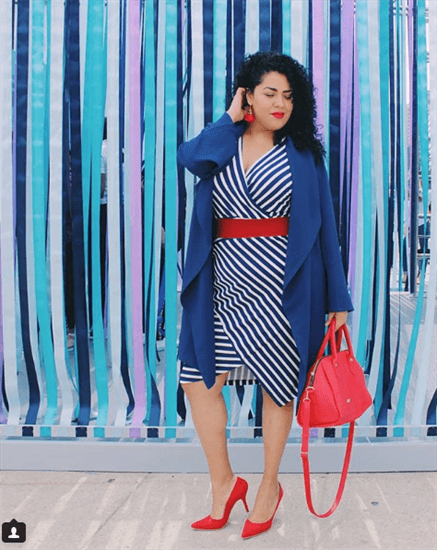 Influencer Arhe Molina wearing blue striped dress with red belt in front of streamers