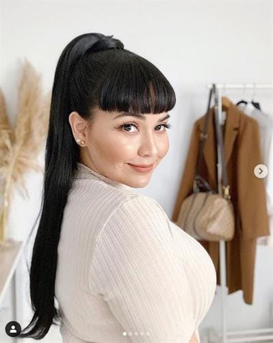 Puerto Rican influencer Sandra Lobos in a white turtleneck looking over her shoulder and smiling