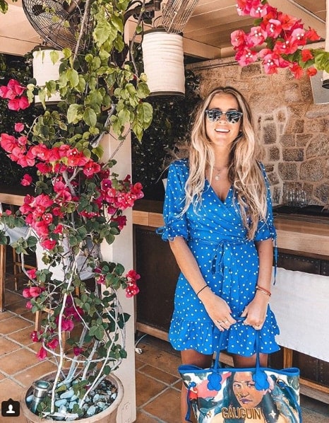Influencer Janni Deler in blue polka dot dress under flower roof