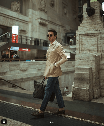 Influencer Marco Taddei in cream trench coat and jeans carrying duffle bag