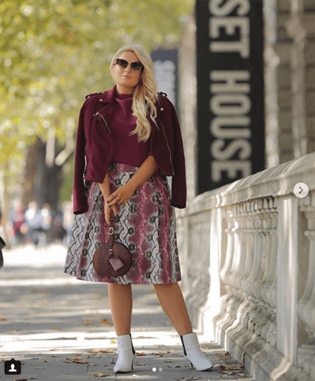 Blogger Louise O'Reilly wearing maroon jacket and patterned skirt with white booties