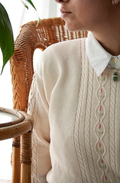 woman wearing beige sweater with white collared shirt and necklace