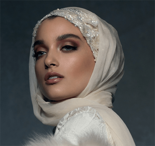 model wearing ornate pearl hijab in ivory against a dark backdrop